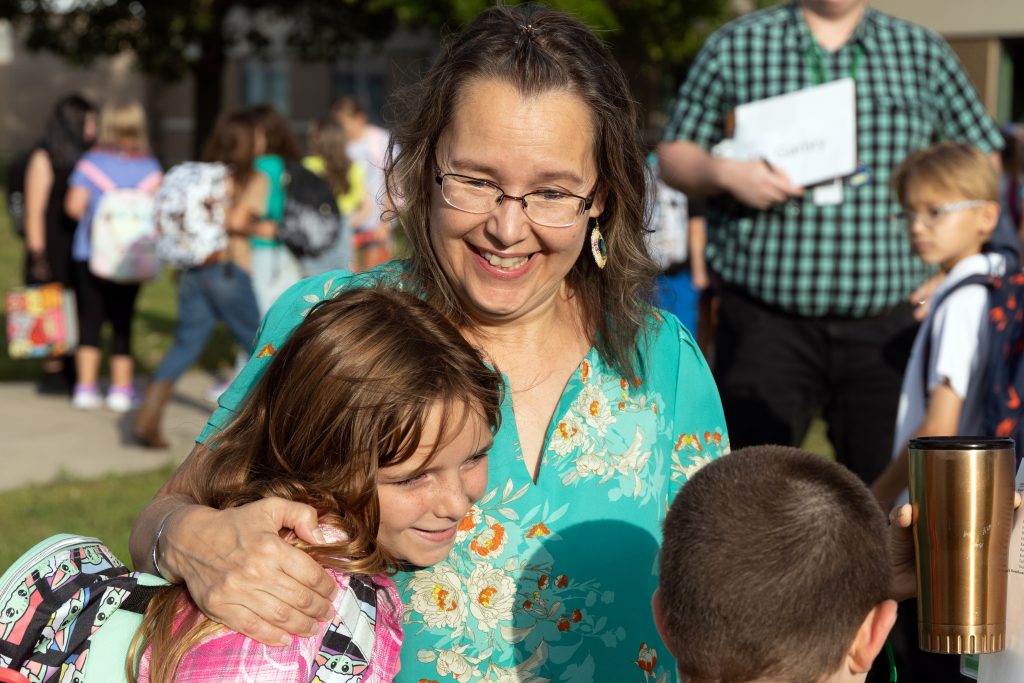 A teacher warmly receive a hug from a student