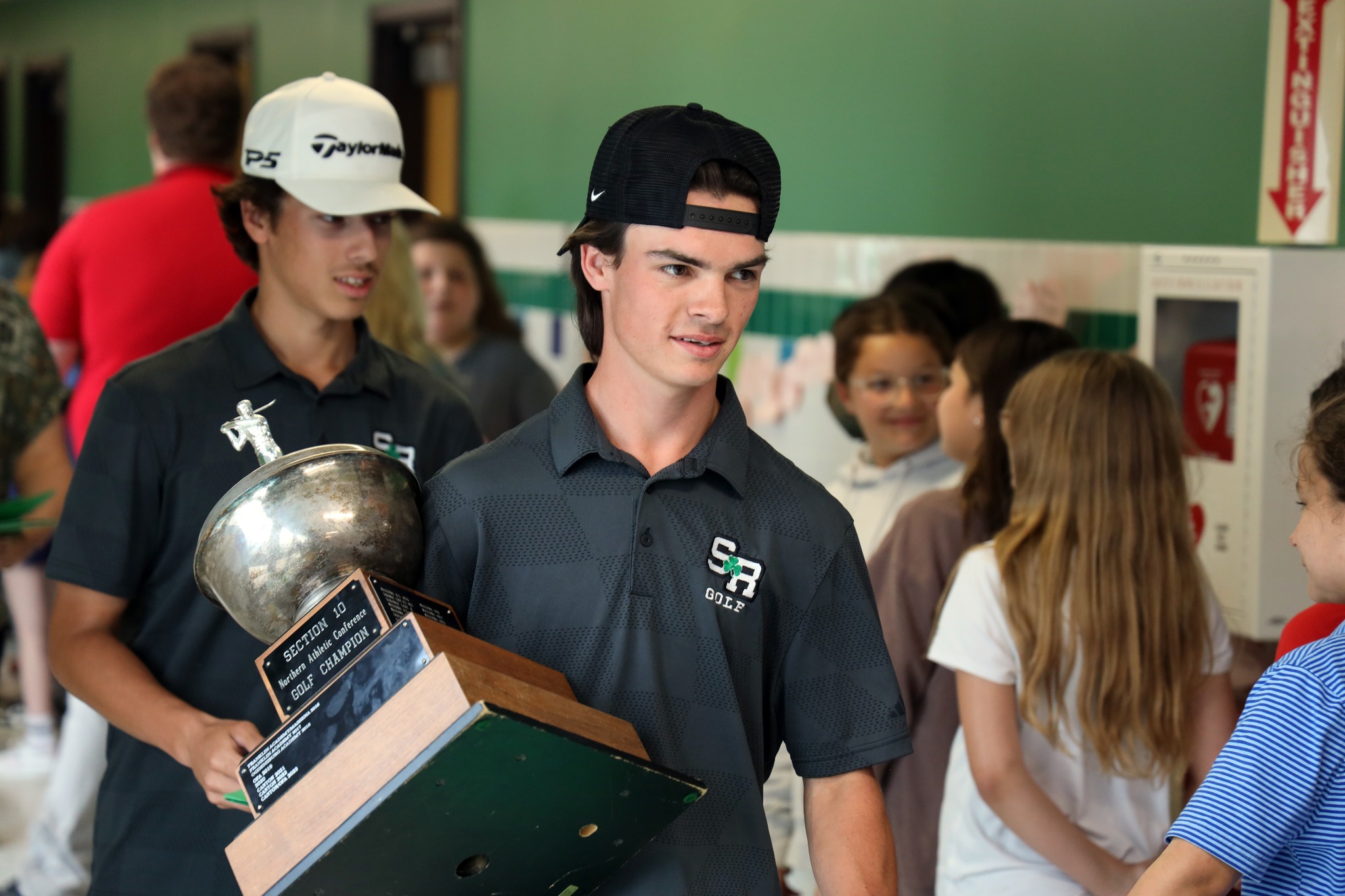 A golf athlete walks through the halls carrying a large trophy