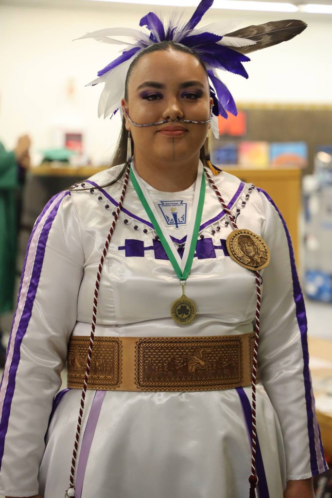 A National Honor Society student wears a headdress and a medal for academic achievement