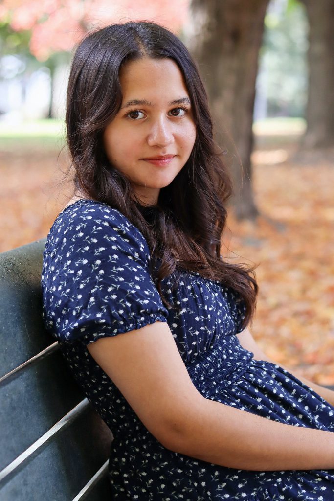 Image of a young woman sitting on a bench in a park setting