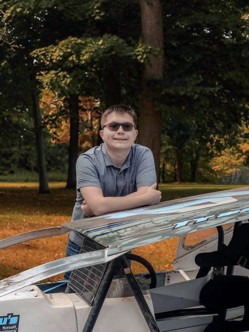 Image of a young man leaning against a race car