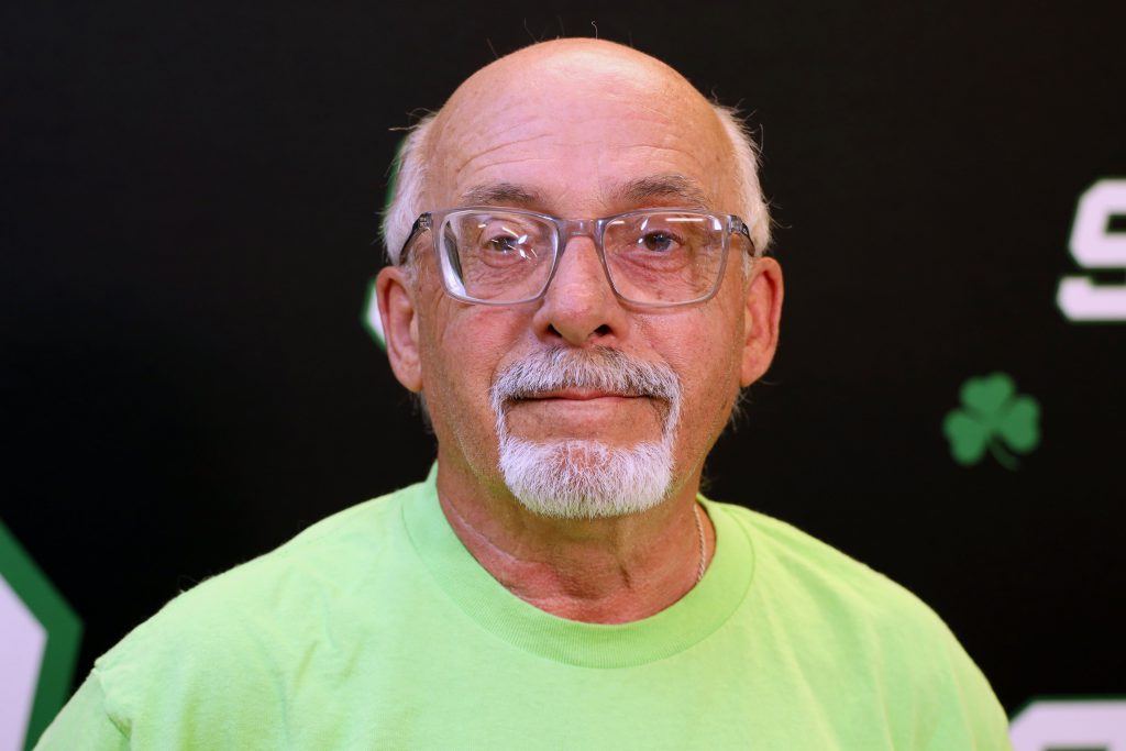 Man smiling in front of a back drop with the letters SR on it