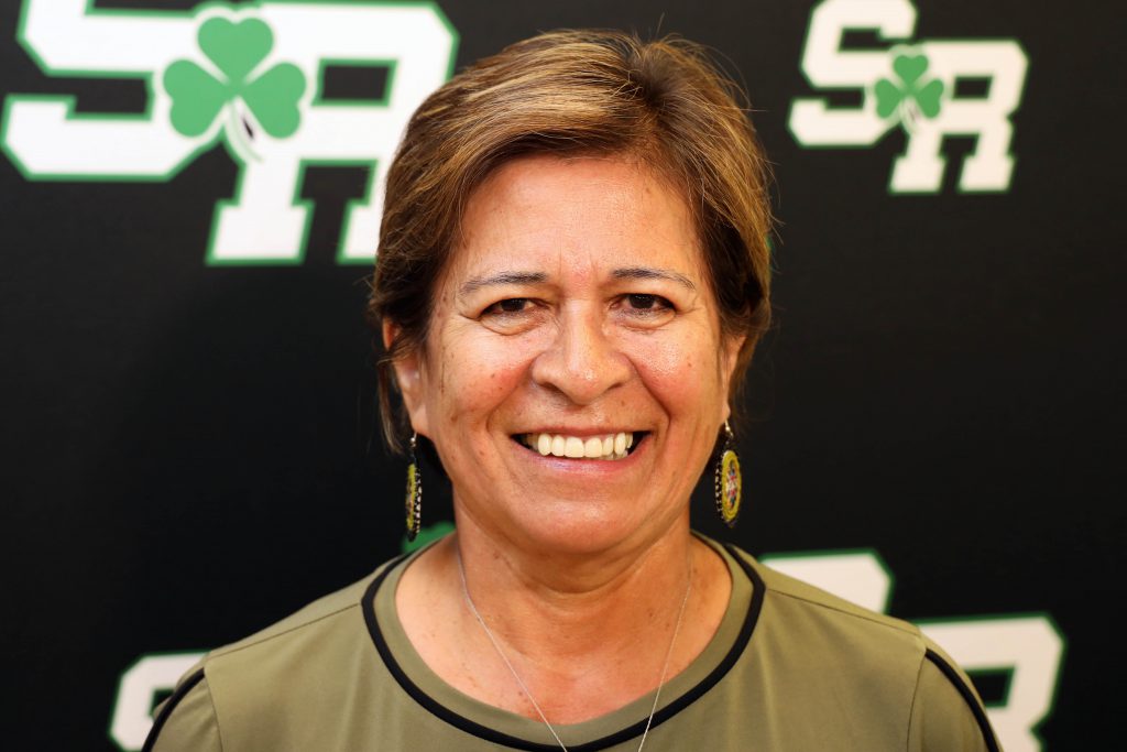 Woman smiling in front of a back drop with the letters SR on it