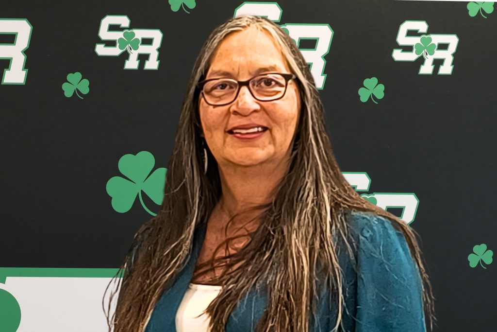 Woman smiling in front of a back drop with the letters SR on it