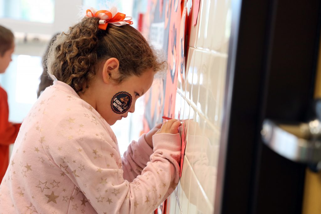 A child work to tape an item to a wall