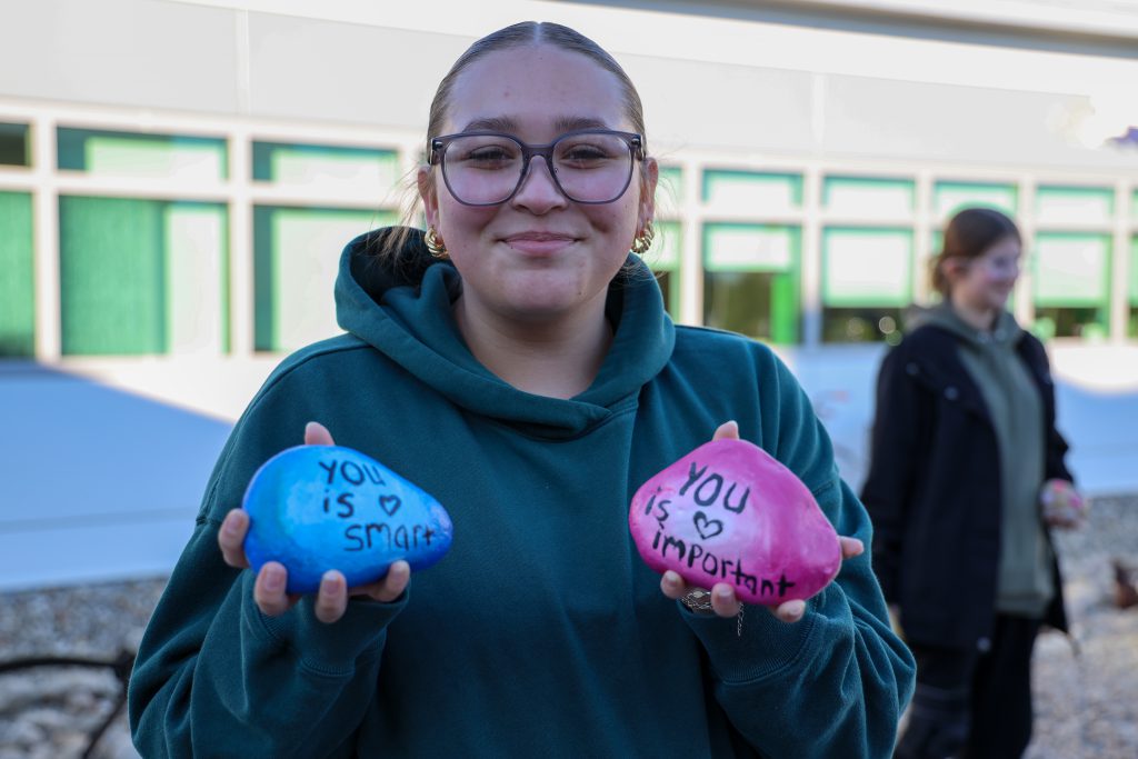 A student holding up two colorful rocks that say ' You is smart' and 'you is important'