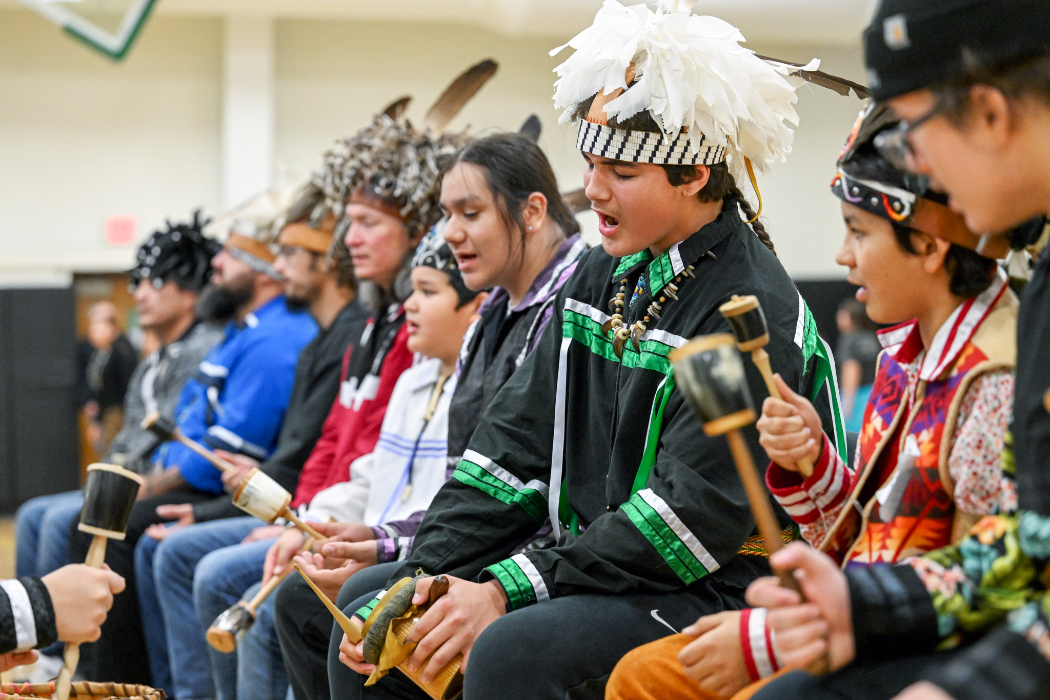 Several people signing outfitted in tribal regalia