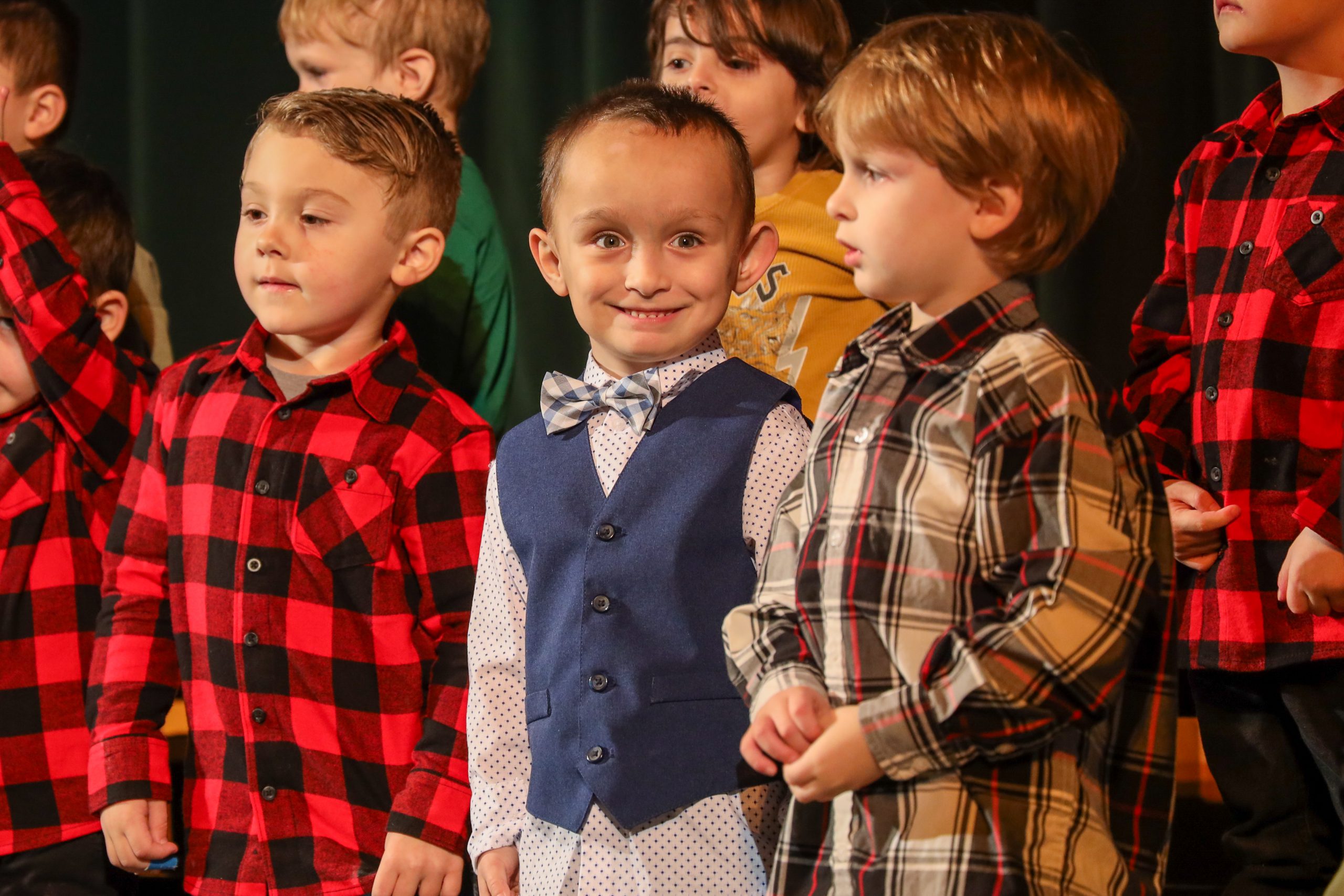 A boy smiling while standing next to two other boys