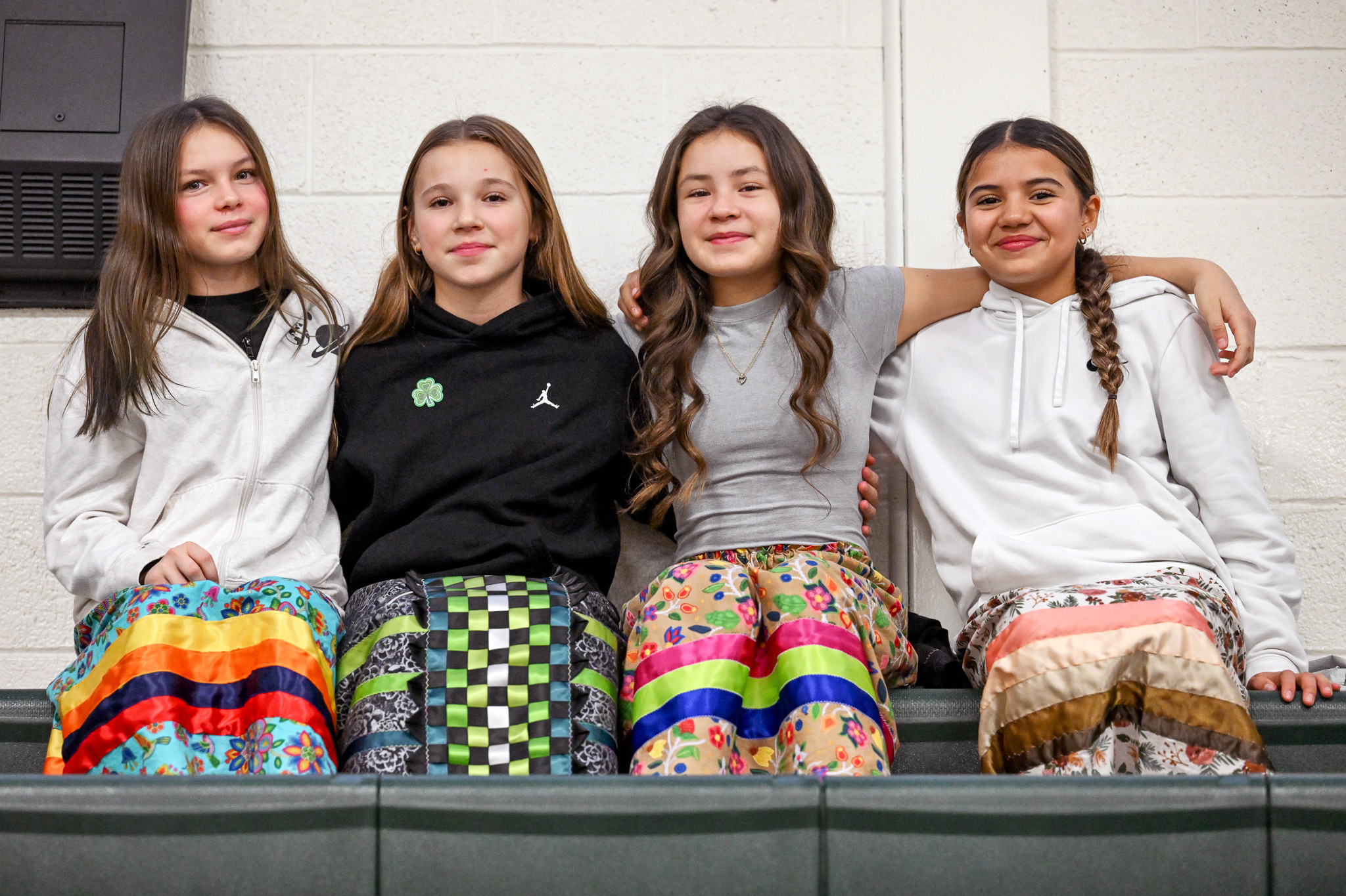 Four students sit next to each other on indoor bleachers